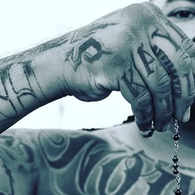Tattooed hands holding a rosary